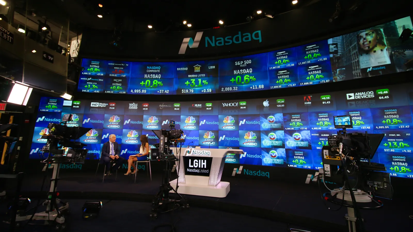 Nasdaq MarketSite studio in Times Square with walls of live stock tickers above the broadcast desk.