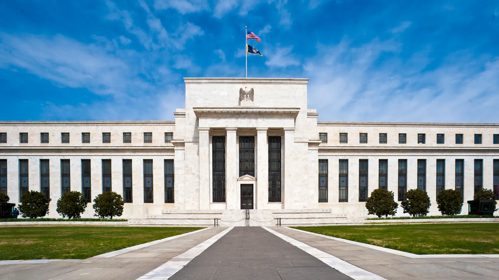 The Marriner S. Eccles Federal Reserve Board Building in Washington under a bright blue sky.