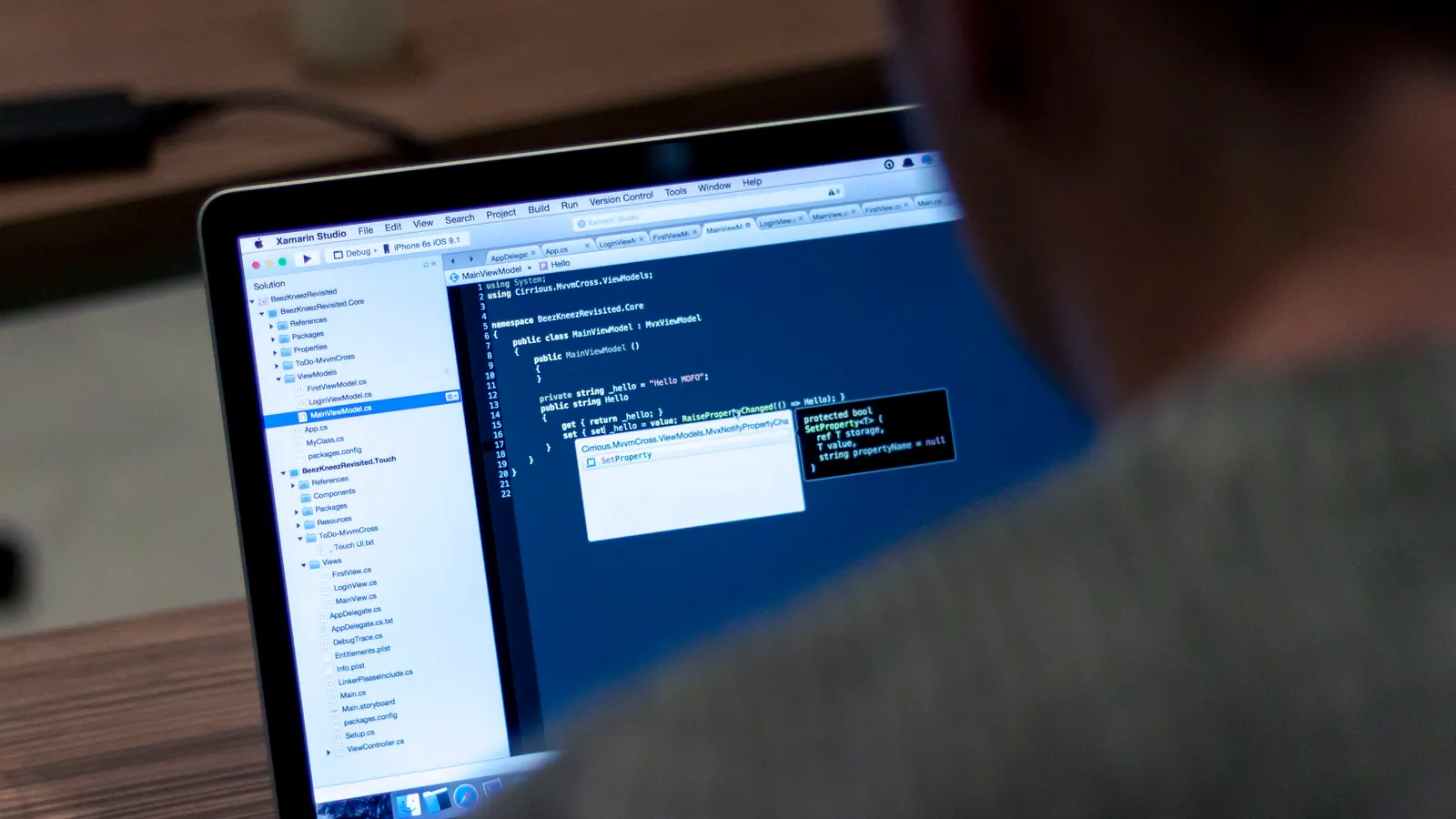 A developer writing code in an editor on an open laptop at a desk.
