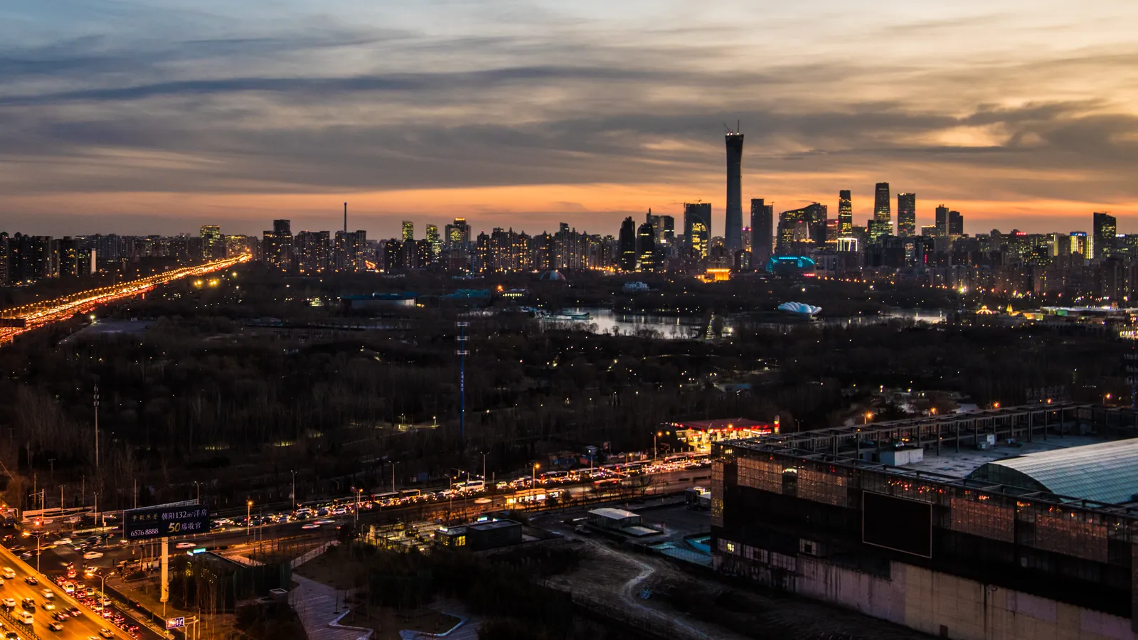 The Beijing skyline at dusk, seen over the traffic of the northeast Fourth Ring Road.