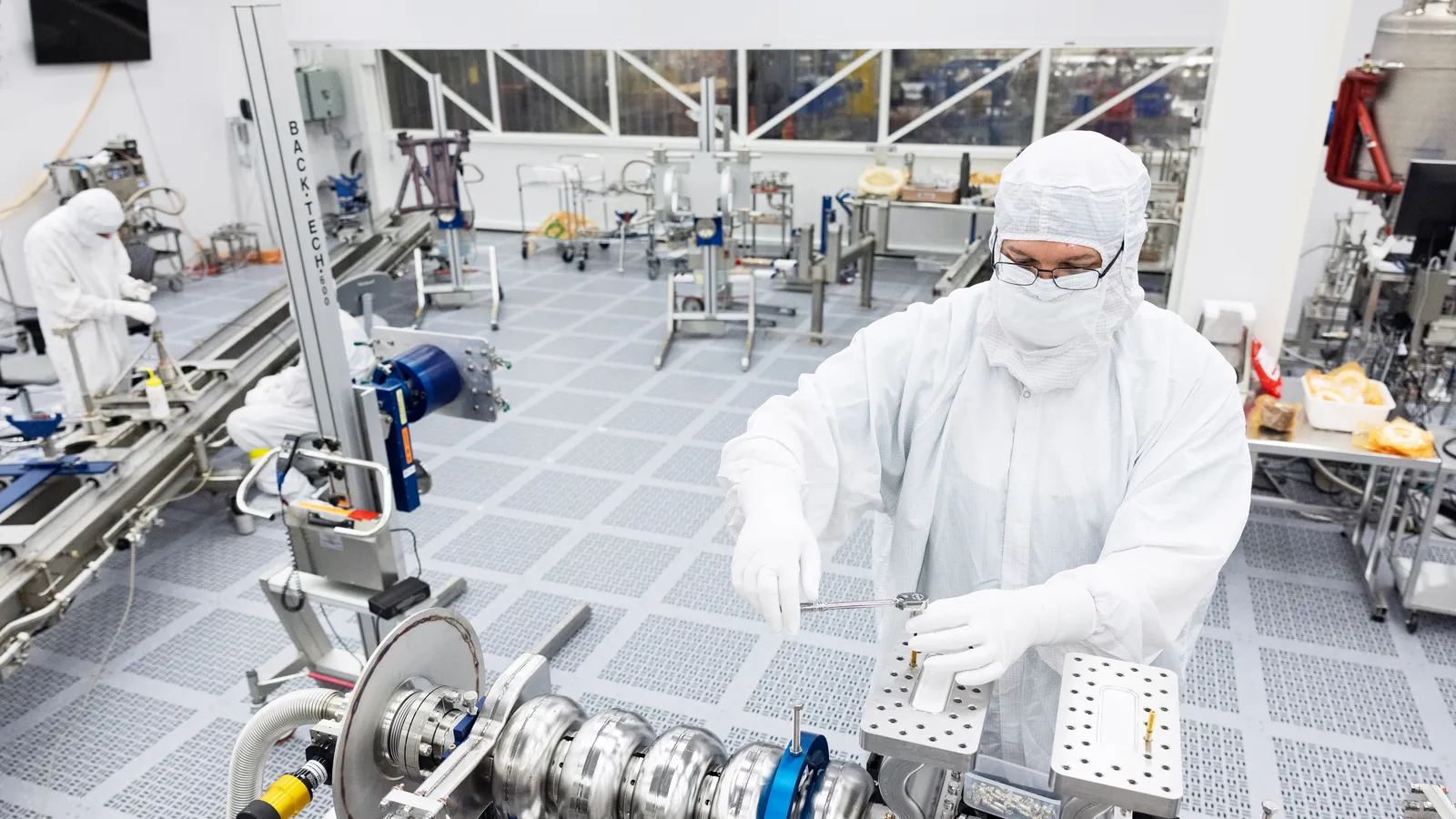 Technicians in white cleanroom suits working at semiconductor manufacturing equipment