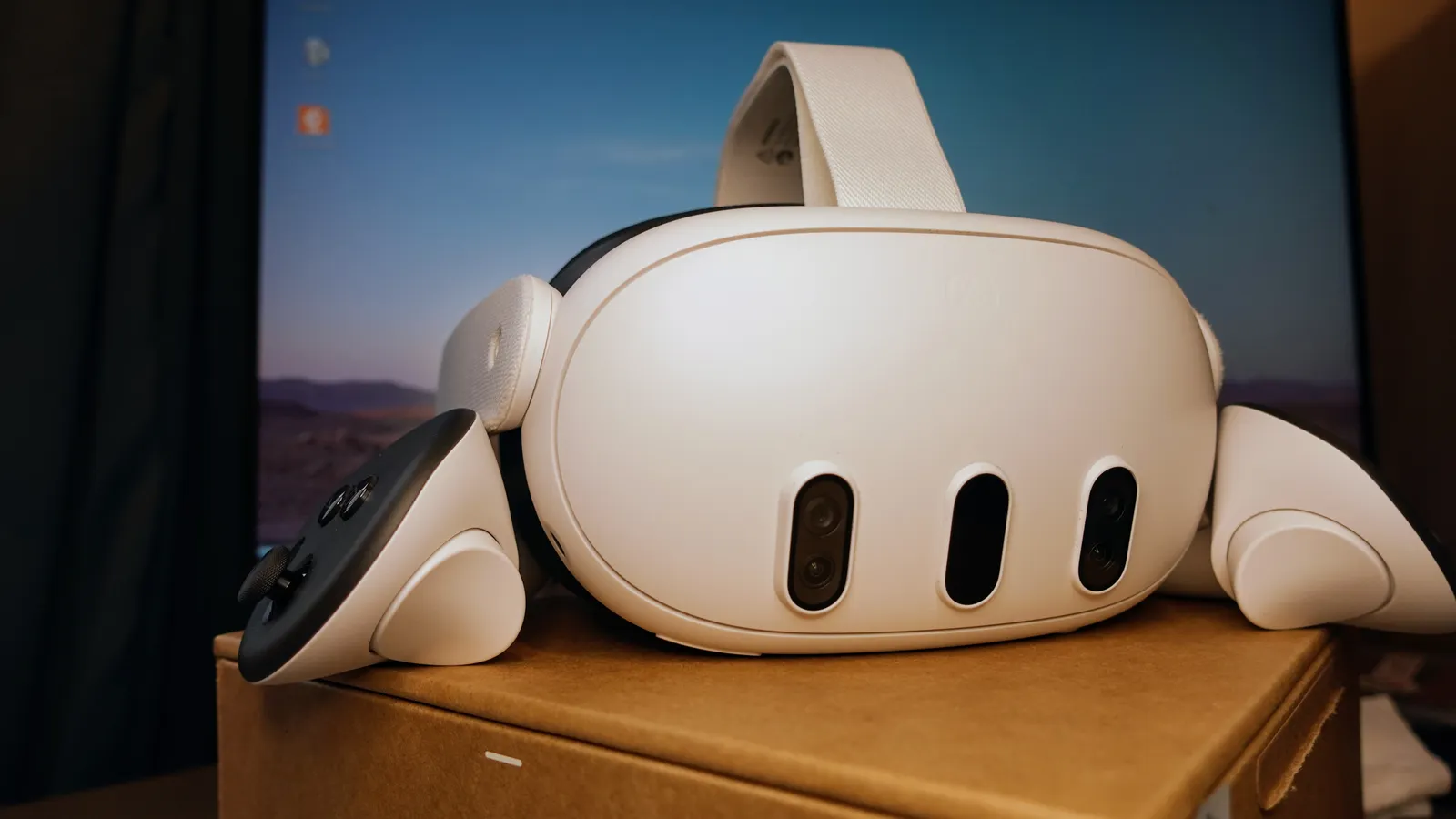 A white Meta Quest 3 headset shown from the front, its controllers resting beside it.