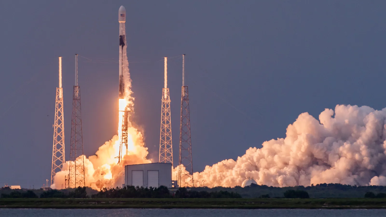 A SpaceX Falcon 9 rocket lifting off from its launch pad in a cloud of exhaust.